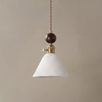A cone-shaped white ceramic Clérachic pendant with a star pattern in relief, under a round walnut ball and brass switch.