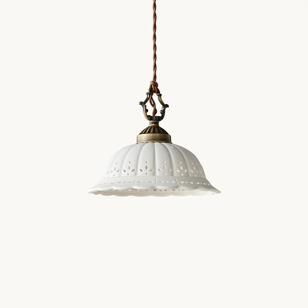 White ceramic dome shade with pierced flower cut-outs and a scalloped rim, hung from an antique brass top and a twisted cord, this Clérachic pendant on white.