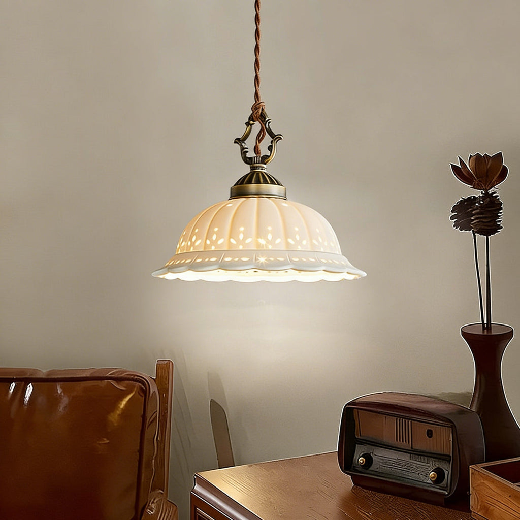 Lit white ceramic dome of this Clérachic pendant beside a vintage radio and a tan leather chair, on a wooden desk.