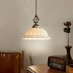 Lit white ceramic dome of this Clérachic pendant beside a vintage radio and a tan leather chair, on a wooden desk.
