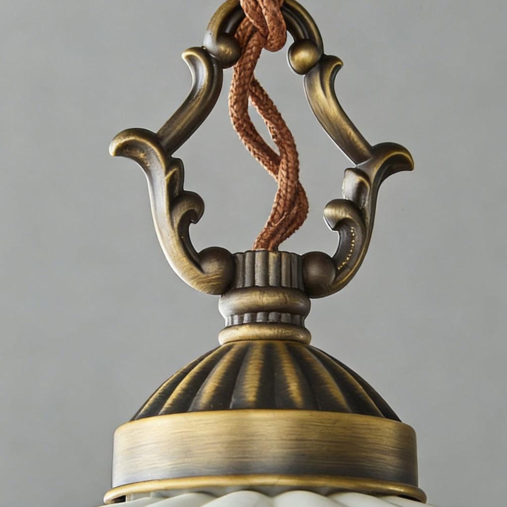 Close view of the scrolled antique brass top and twisted cord above the dome of this Clérachic pendant.