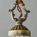 Close view of the scrolled antique brass top and twisted cord above the dome of this Clérachic pendant.
