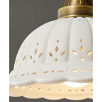 Close view of the flower-shaped cut-outs and scalloped rim on this Clérachic pendant's white ceramic dome, lit from inside.