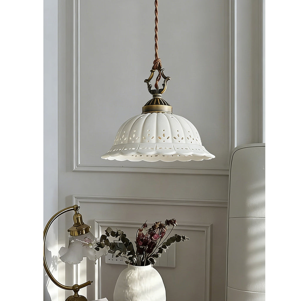 This Clérachic pendant hangs by a panelled wall, with an arched brass lamp and a white vase of dried flowers below.