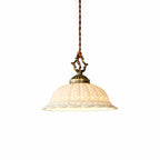 Cream-lit ceramic dome with a scalloped rim on a twisted cord and antique brass cap, this Clérachic pendant on a white backdrop.