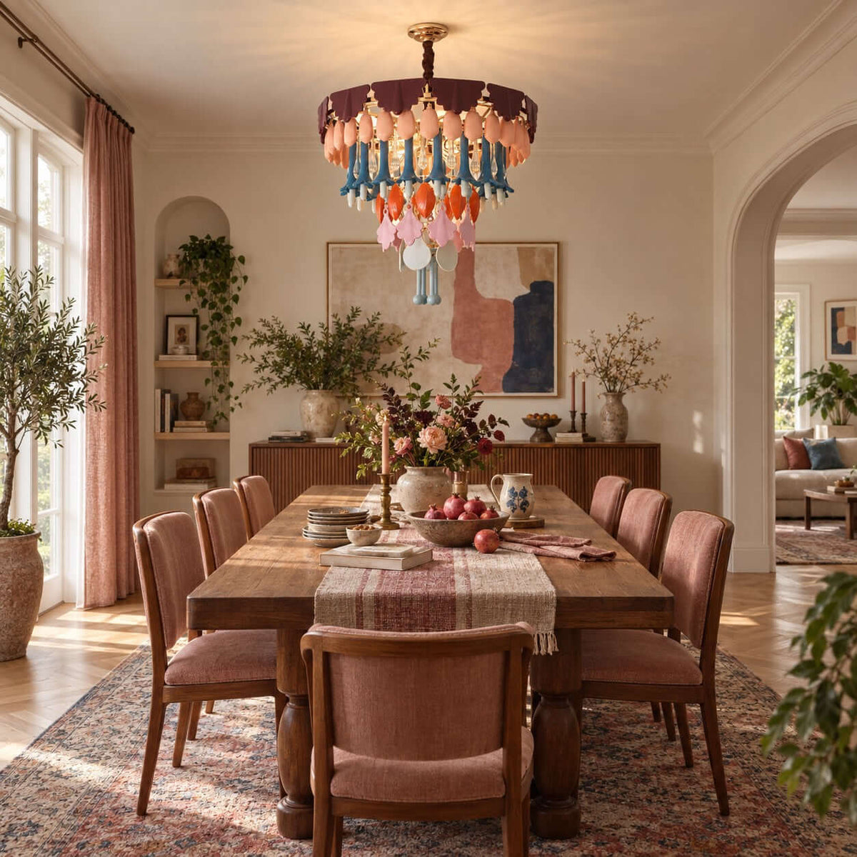 The Clérachic chandelier above a long wooden dining table with blush-pink chairs, with a pale arched doorway behind.
