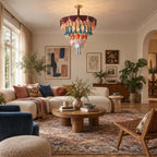 The Clérachic ceramic chandelier hangs above a seating area with a cream sofa, a blue velvet chair and a patterned rug.