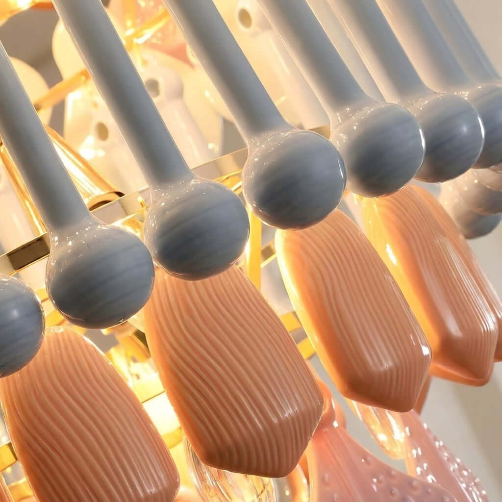 Close view of the glossy grey-blue ceramic beads and ribbed peach drops lit from within on this Clérachic chandelier.