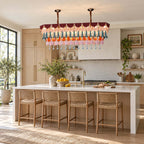 A rectangular Clérachic chandelier on two chains above a stone-topped kitchen island with four woven bar stools and warm light.