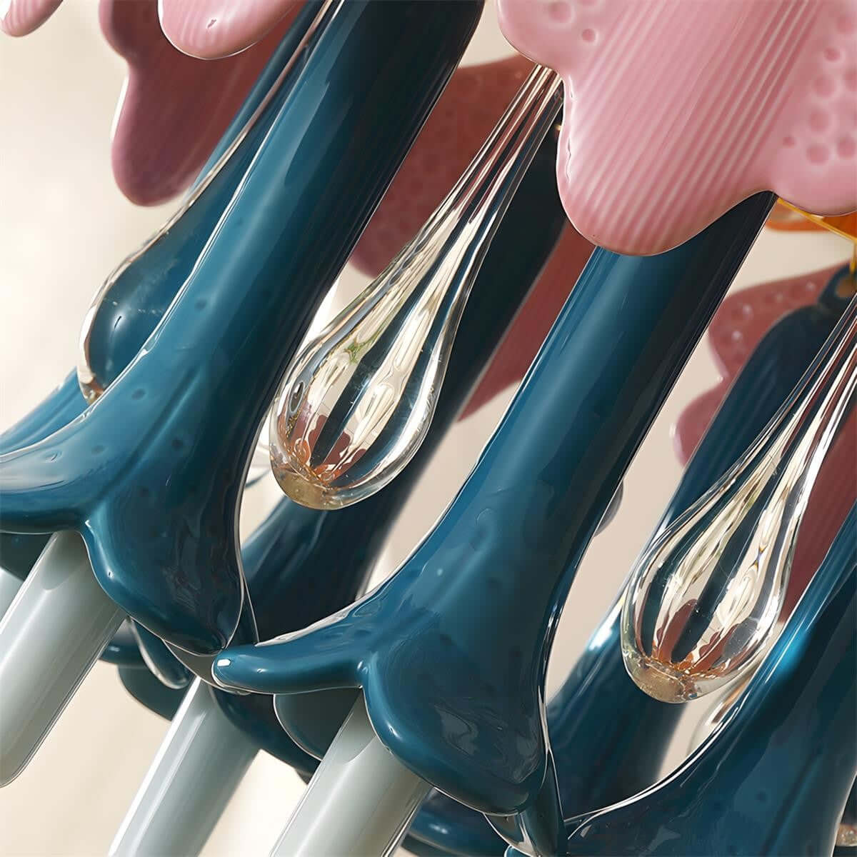 Close view of the glossy teal ceramic stems and clear glass drops on this Clérachic chandelier, with pink petals above.