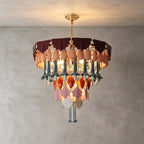 A round Clérachic chandelier with tiers of ceramic and glass drops, lit against a grey plaster wall and ceiling.