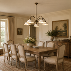 This Clérachic chandelier with curved brass arms and white shades above a long wooden dining table and upholstered chairs.