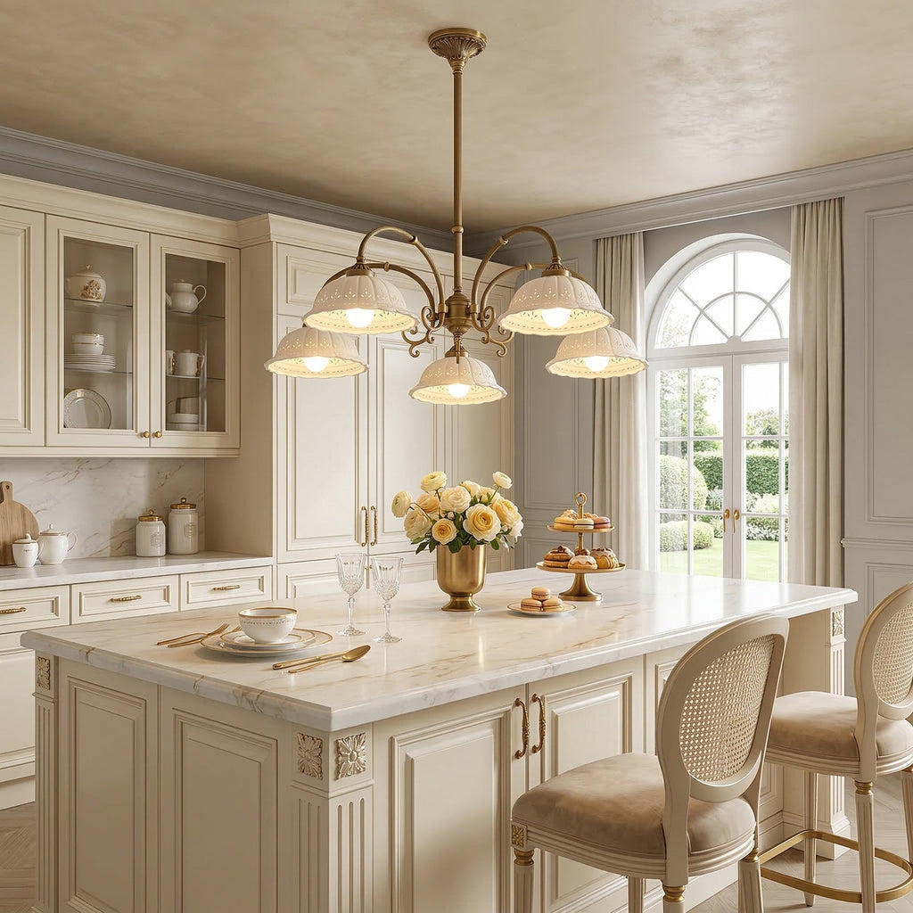 Clérachic chandelier with ceramic shades above a marble-topped kitchen island, with an arched glazed door and cream cabinets behind.