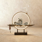 Clérachic Waves-finish incense burner lamp, a pale celadon wave sculpture with prayer beads hanging beside its glowing ring.