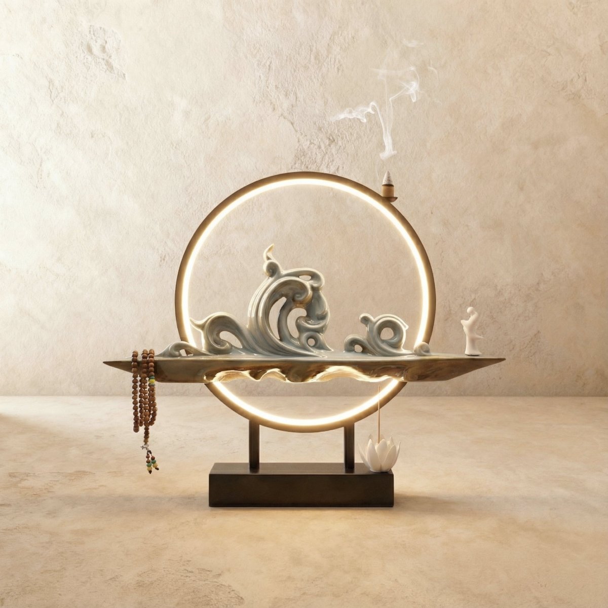 Clérachic Waves-finish incense burner lamp, a pale celadon wave sculpture with prayer beads hanging beside its glowing ring.