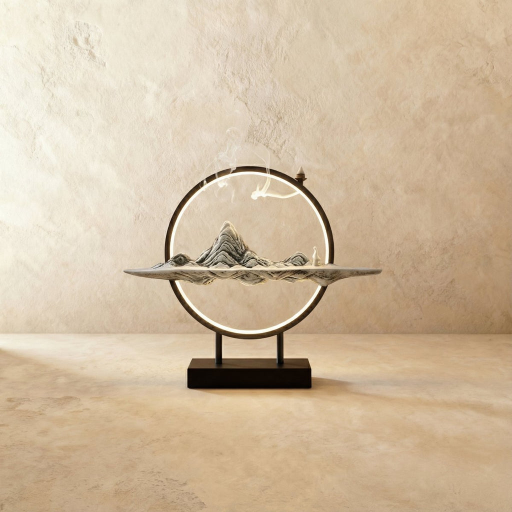 Clérachic Gray Mountain incense burner lamp, a pale ridged peak sculpture with a small figure on a slim tray and lit ring.