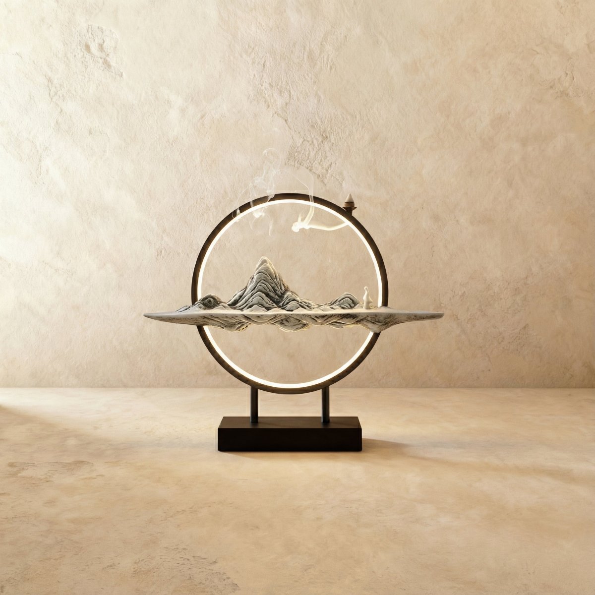 Clérachic Gray Mountain incense burner lamp, a pale ridged peak sculpture with a small figure on a slim tray and lit ring.