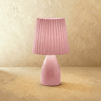 The Clérachic ceramic table lamp in pink, its base topped with a matching pleated fabric shade, unlit.