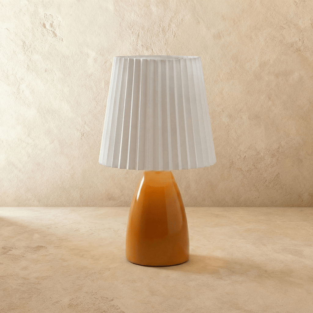 A second angle of the Clérachic orange ceramic table lamp, its pleated white fabric shade shown unlit.