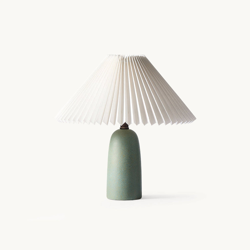 This Clérachic table lamp on a plain white backdrop, with a white pleated conical shade over a smooth green ceramic base.