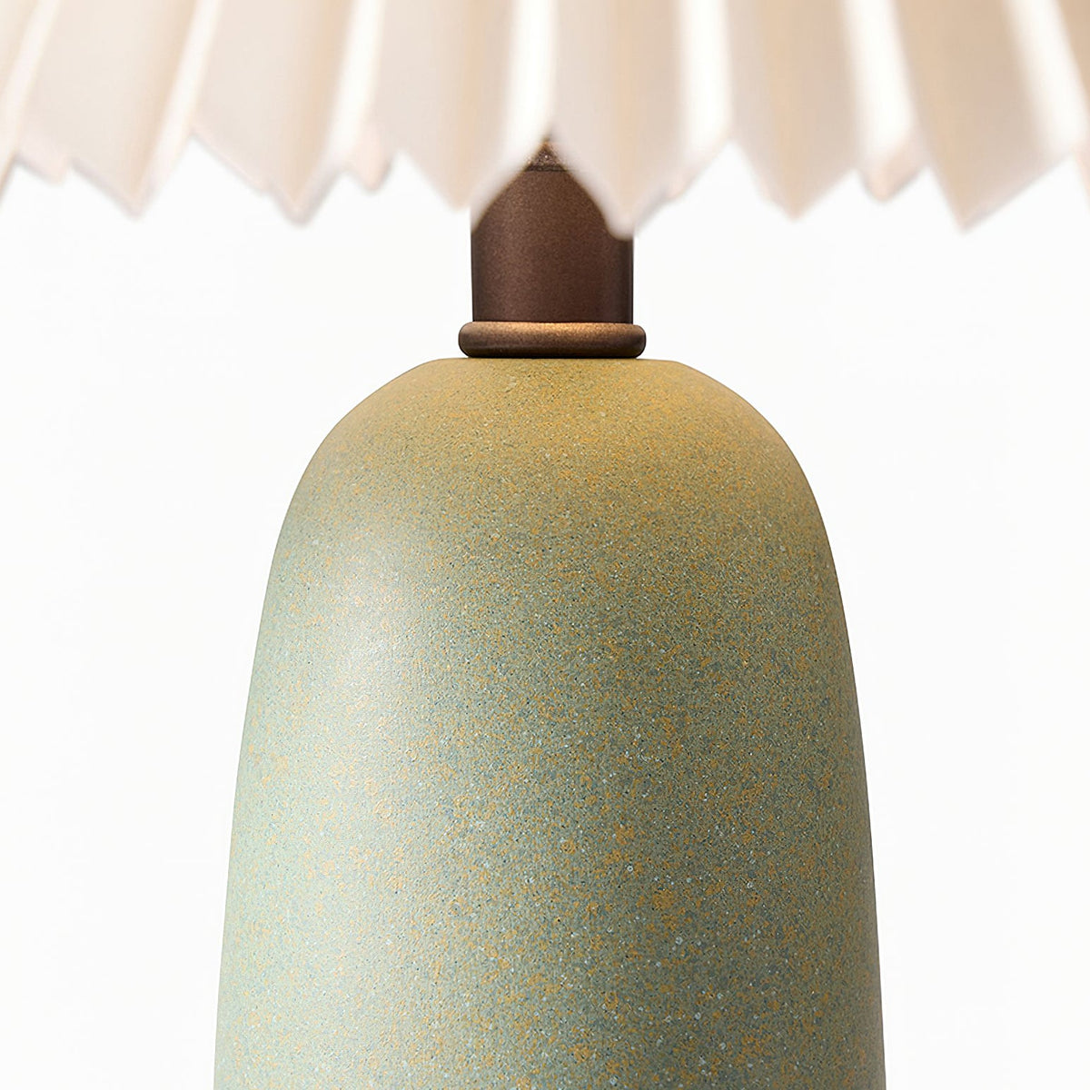 Close view of the speckled green glaze on the ceramic base of this Clérachic table lamp, with the dark wooden neck above.