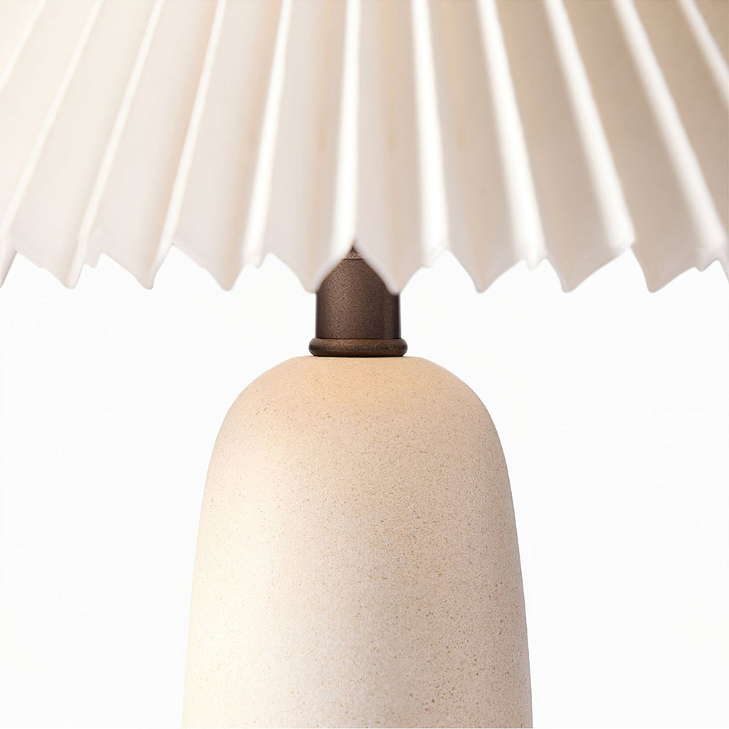 Close view of the beige ceramic base of this Clérachic table lamp, with its speckled finish and dark neck under the pleated shade.