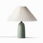 A short green Clérachic table lamp with a wide pleated shade and a clear cord, unlit on a plain white backdrop.
