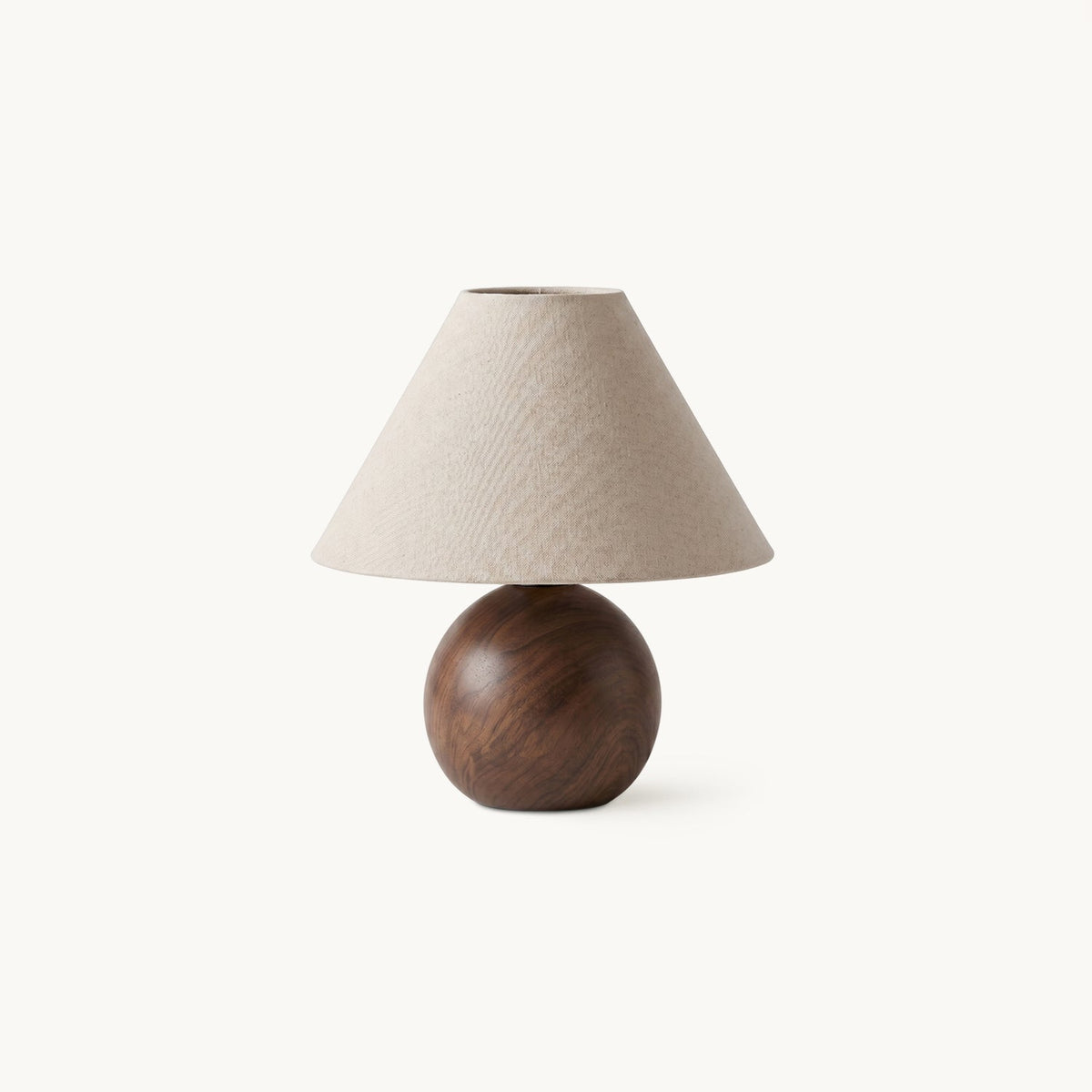 Table lamp from Clérachic with a conical linen shade on a round walnut wood-grain ceramic base, shown on a white backdrop.