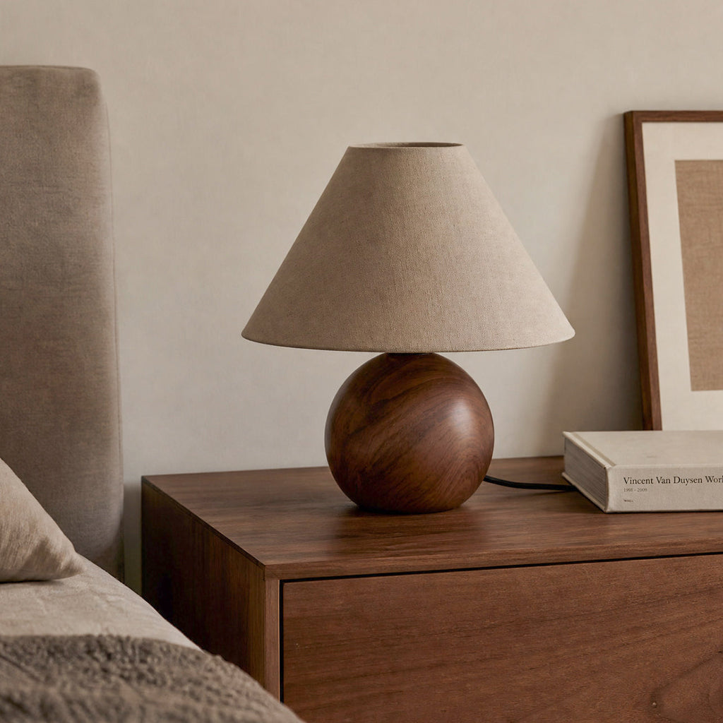 Unlit Clérachic table lamp with a natural linen shade and walnut-grain base on a chest of drawers, with a framed print behind.