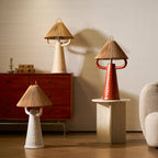 Three of these table lamps in cream, terracotta and white on a walnut cabinet, a stone plinth and the floor, beside a boucle armchair; Clérachic.