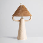 Front view of the cream Clérachic table lamp, its brass stem showing under the woven shade between the two curved arms.