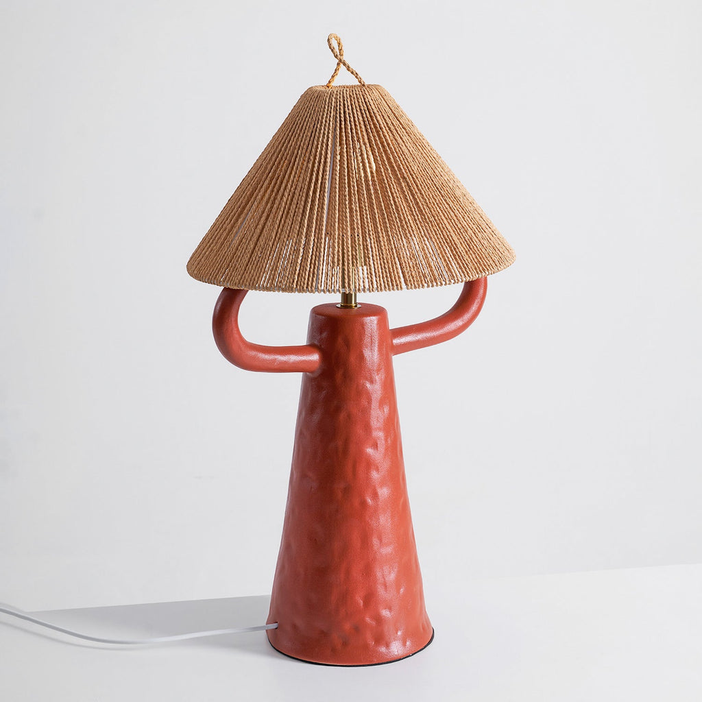 This Clérachic table lamp in terracotta, seen slightly from the side, with a white cord running from the base to the left.