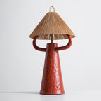 Terracotta ceramic table lamp with a slim brass stem, rounded arms and a natural rope cone shade, on a pale grey backdrop; Clérachic.