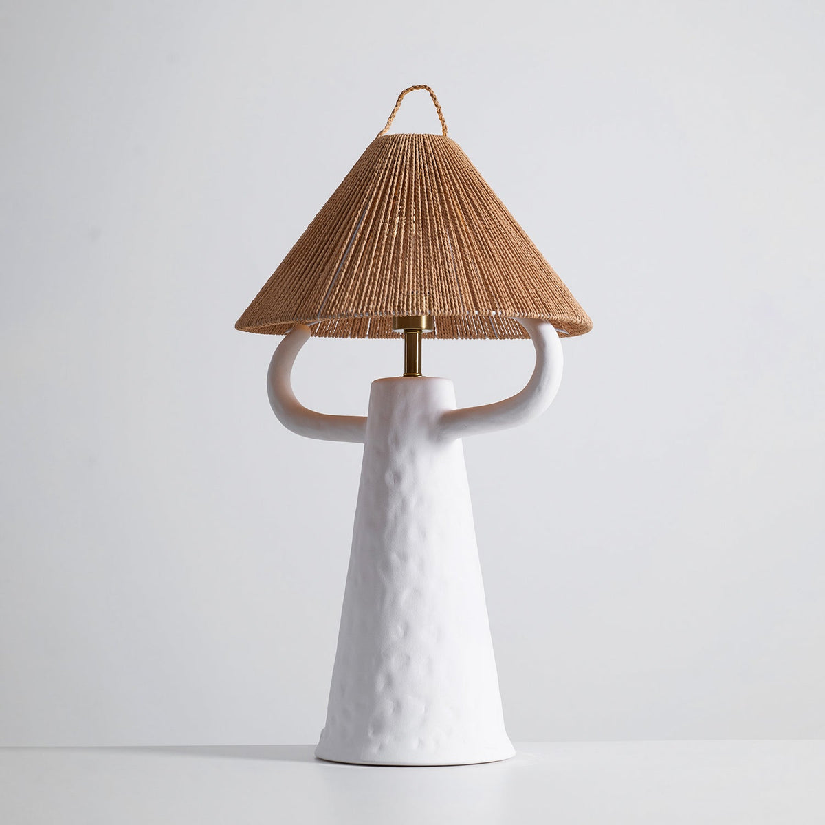 Smaller view of the white Clérachic table lamp, the dimpled tapering body and curved arms under a twisted rope shade.