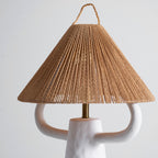 Rope shade of this Clérachic table lamp seen from slightly below, the cone of twisted strands above two white ceramic arms and a brass stem.