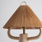 Cream ceramic arms reach under the rope cone shade, with the brass stem and lamp holder showing between them; from Clérachic.