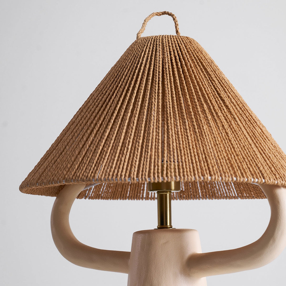 Cream ceramic arms reach under the rope cone shade, with the brass stem and lamp holder showing between them; from Clérachic.