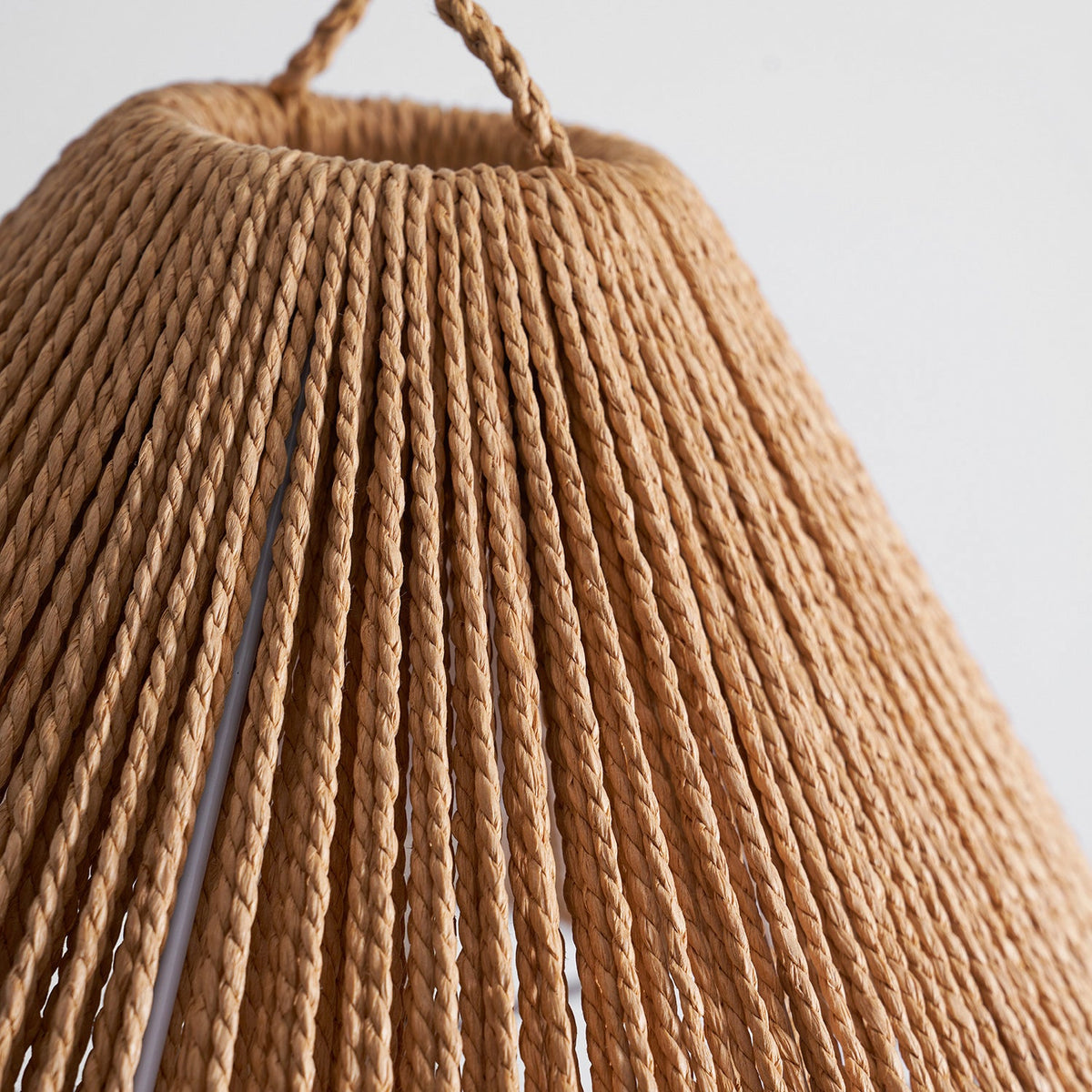 Detail of the twisted paper-rope strands on the shade of this Clérachic table lamp, with its braided loop at the top.