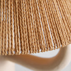Close view of the loose rope strands along the lower rim of the shade, with a cream ceramic arm below; from Clérachic.
