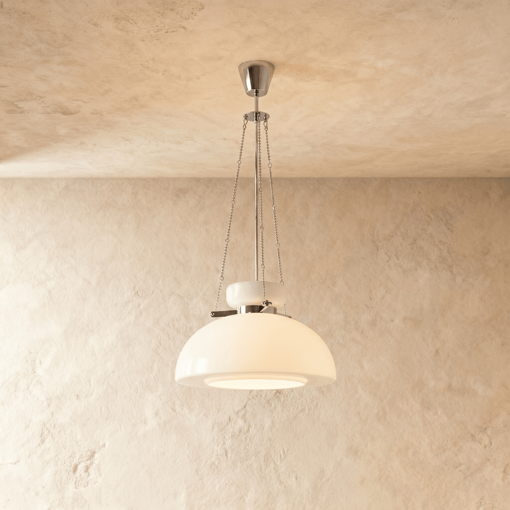 Clérachic white glass dome pendant hung on fine chains from a chrome canopy, against a warm plaster wall.