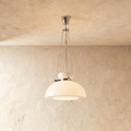 Clérachic white glass dome pendant hung on fine chains from a chrome canopy, against a warm plaster wall.