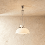 Clérachic white glass dome pendant hung on fine chains from a chrome canopy, against a warm plaster wall.