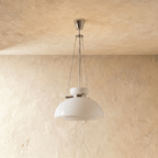 Clérachic white glass dome pendant on slim chains and a chrome canopy, switched off in front of a plaster wall.