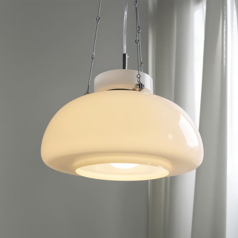 Close view of a lit Clérachic white glass dome pendant, with its stepped diffuser, chain links and chrome fittings, by a sheer curtain.