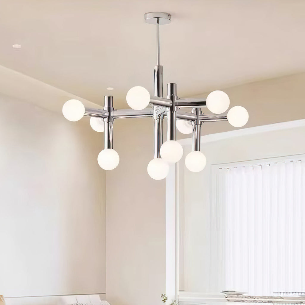 Chrome and frosted-glass chandelier from Clérachic in a warm-toned room with a tall window and sheer vertical blinds.