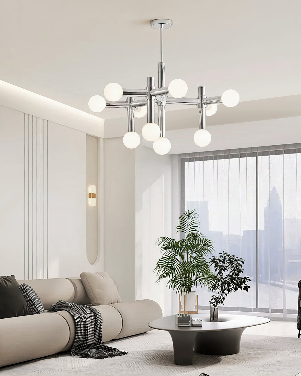 Clérachic chrome chandelier in a pale room with a curved beige sofa, a low round table and a city view beyond the glass.