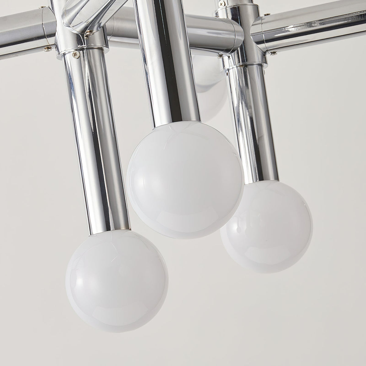 Close view of three frosted glass spheres on polished chrome tube arms, from the underside of this Clérachic chandelier.