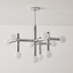 Unlit Clérachic chandelier against a pale wall, its chrome crossing arms and ten white globes hanging from a thin rod.