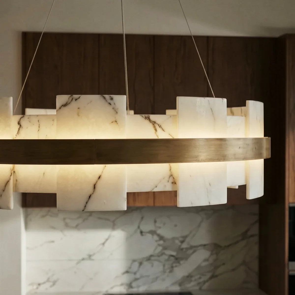 Close crop of Clérachic alabaster panels with dark veining, lit from within and edged with a brushed brass band.
