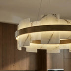 Underside view of a Clérachic chandelier, its alabaster segments glowing around a brushed brass ring in a kitchen.